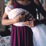 Η μητέρα κρατάει το «μωρό» της τυλιγμένο με λευκό πέπλο