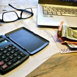 Χρήματα, γυαλιά και κομπιούτερ σε τραπέζι για τον υπολογισμό φόρου
