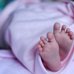 Πατουσάκια μωρού εξέχουν από τη κουβέρτα