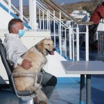 Ιδιοκτήτης με τον σκύλο του με μάσκα στο πλοίο