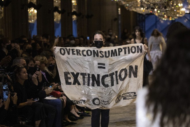 Διαδηλώτρια με πανό που γράφει «Υπερκατανάλωση = Αφανισμός» - φωτογραφία ΑΡ