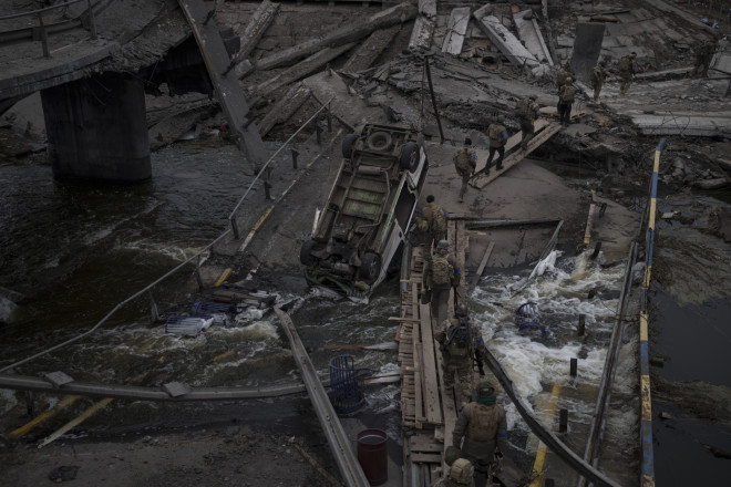 Ξένοι και Ουκρανοί στρατιώτες διασχίζουν ένα αυτοσχέδιο μονοπάτι κάτω από μια κατεστραμμένη γέφυρα στο Irpin, στα περίχωρα του Κιέβου