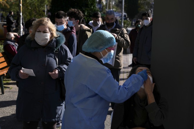 Το ιατρικό προσωπικό πραγματοποιεί ένα γρήγορο τεστ COVID-19 σε μια γυναίκα καθώς άλλοι περιμένουν στην ουρά στην Αθήνα, τη Δευτέρα 3 Ιανουαρίου 2022. (AP Photo/Θανάσης Σταυράκης)