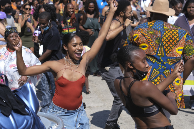 'Ανθρωποι χορεύουν καθώς γιορτάζουν κατά τη διάρκεια μιας εορταστικής μνήμης για την Juneteenth η στο Leimert Park Plaza το Σάββατο, 19 Ιουνίου 2021, στο Λος Άντζελες. (AP Photo/Ringo H.W. Chiu)