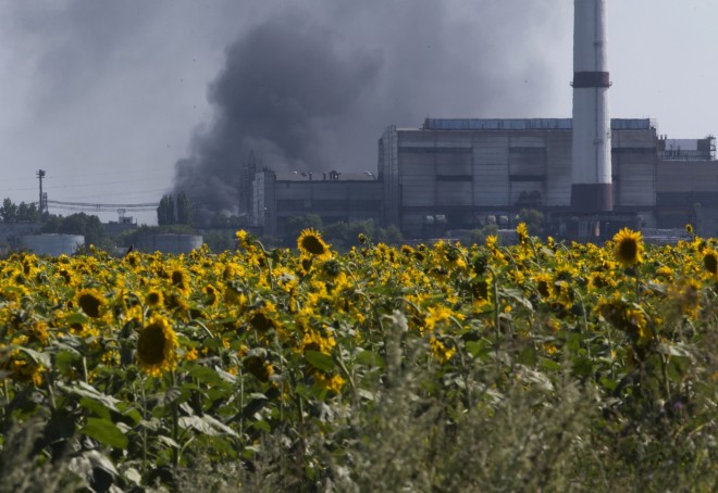 Καπνός από διυλιστήριο πετρελαίου ανεβαίνει πάνω από ένα χωράφι με ηλίανθους κοντά στην πόλη Lisichansk, στην περιοχή Luhansk, στην ανατολική Ουκρανία, 26 Ιουλίου 2014. Οι παγκόσμιες τιμές μαγειρικού λαδιού αυξάνονται από την έναρξη της πανδημίας COVID-19 και ο πόλεμος της Ρωσίας στην Ουκρανία έχει προκαλέσει κόστος σπειροειδής. Είναι η τελευταία επίπτωση στην παγκόσμια προσφορά τροφίμων από τον πόλεμο, με την Ουκρανία και τη Ρωσία να είναι οι κορυφαίοι εξαγωγείς ηλιέλαιου στον κόσμο. Και είναι άλλο ένα αυξανόμενο κόστος που τσιμπάει τα νοικοκυριά και τις επιχειρήσεις καθώς ο πληθωρισμός εκτινάσσεται στα ύψη. (AP Photo/Dmitry Lovetsky, Αρχείο)
