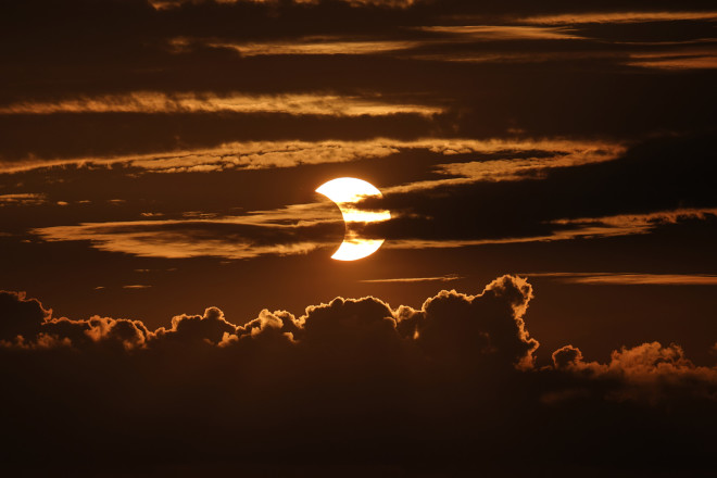 Μια μερική έκλειψη ηλίου ανατέλλει πίσω από τα σύννεφα, Πέμπτη, 10 Ιουνίου 2021, στο Arbutus, Md. (AP Photo/Julio Cortez)