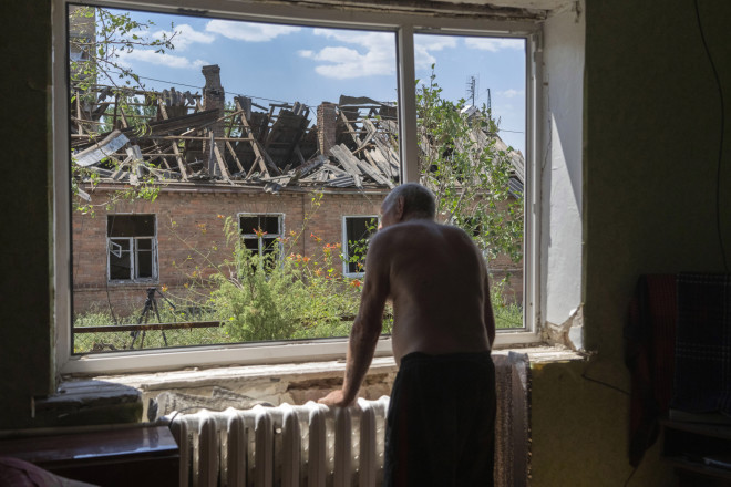 81χρονος Ουκρανός κοιτά από το παράθυρο του σπιτού του στο Μπακχμούτ τις καταστροφές από ρώσικη ρουκέτα- AP Photo/Efrem Lukatsky, File