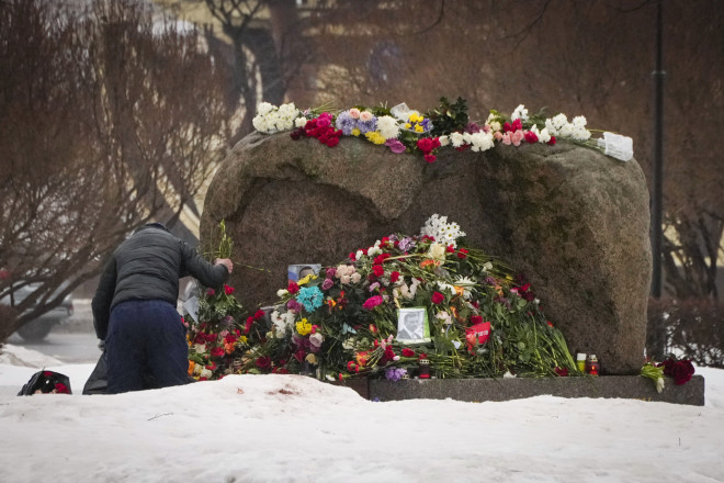 Άνδρας απομακρύνει τις φωτογραφίες του Ναβάλνι από μνημείο στη Ρωσία/ AP Photo/Dmitri Lovetsky