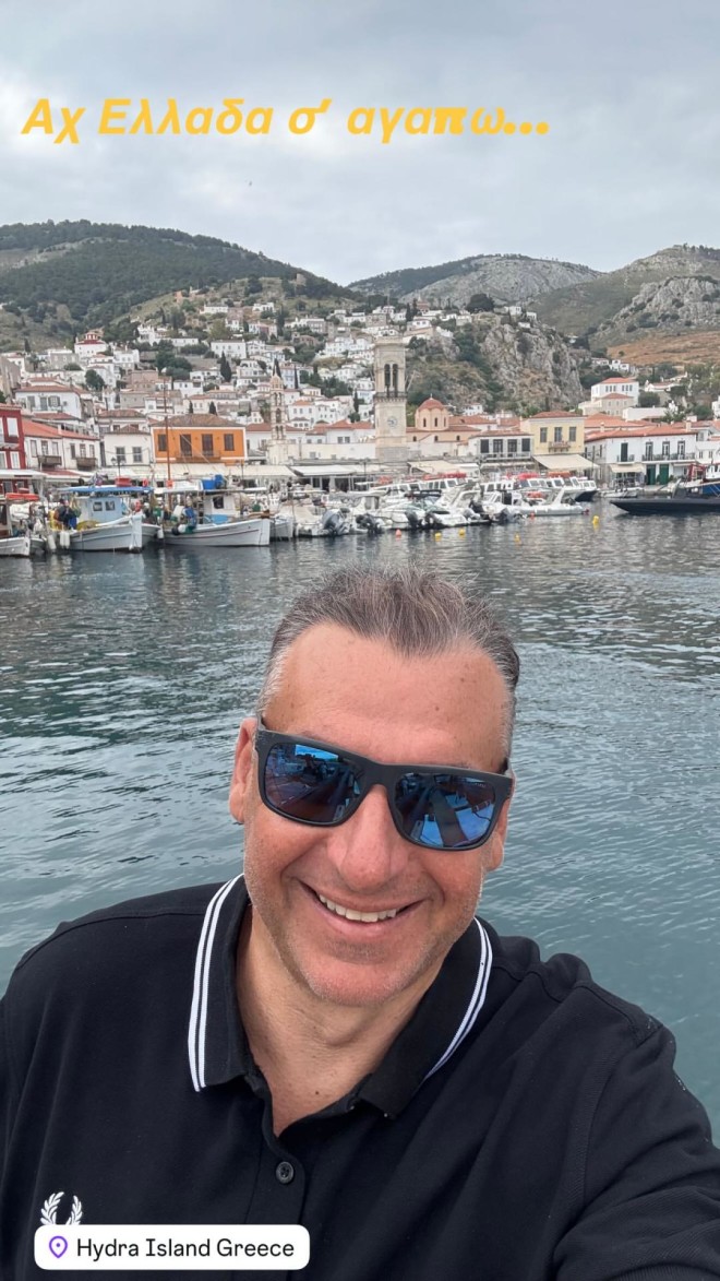Η πόζα του Γιώργου Λιάγκα με φόντο το λιμάνι της Ύδρας