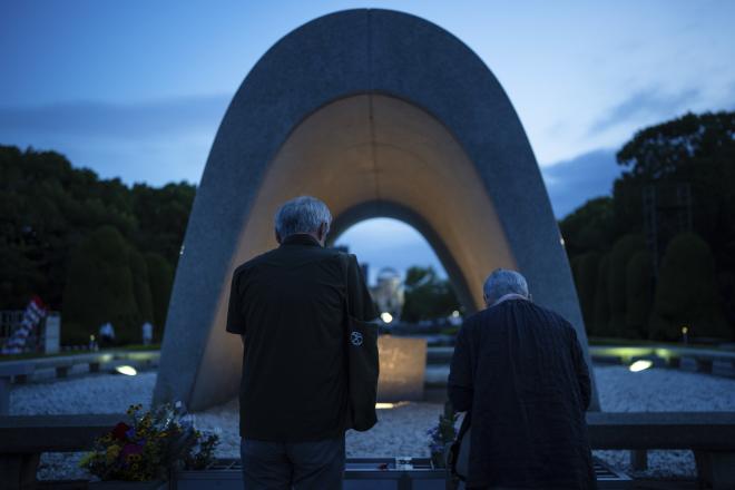 Άνθρωποι προσεύχονται για τα θύματα της ατομικής βόμβας μπροστά από το Κενοτάφιο στη Χιροσίμα/ AP Photo/Louise Delmotte